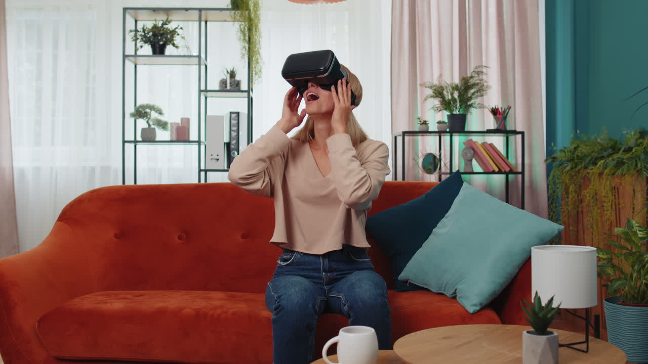 una mujer joven usa gafas de realidad virtual en casa, disfrutando del concepto de video moviendo las manos en el aire