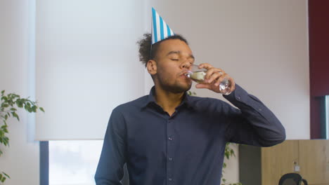 Handsome-American-Man-Drinking-Champagne-And-Looking-At-The-Camera-During-A-Party-At-The-Office