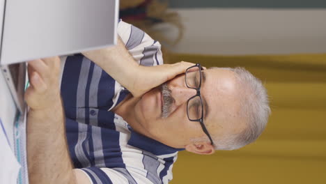 video vertical de un anciano trabajador de la oficina en casa quedándose dormido.