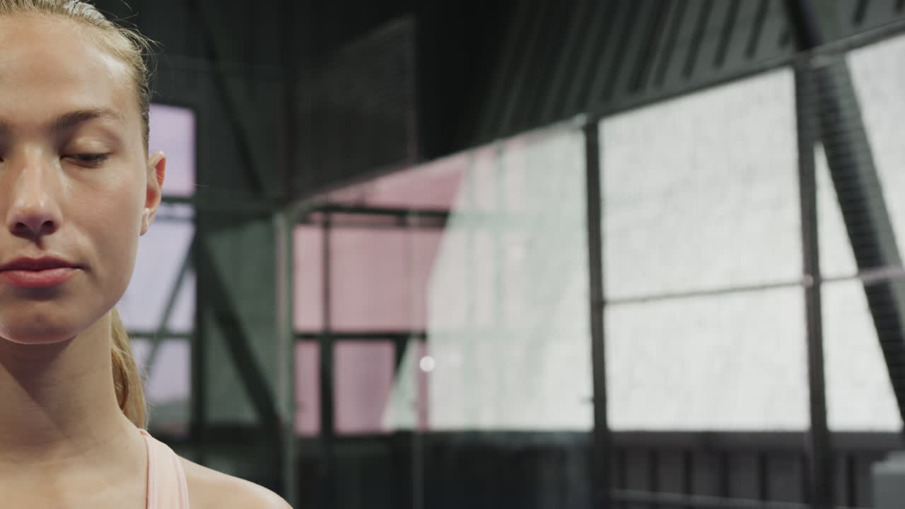 Young woman smiling confidently on indoor padel tennis court, ready to play, copy space