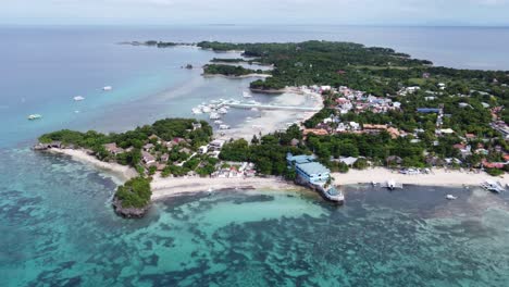 malapascua island in an aerial long shot with dive resorts on logon and bounty beach as diving boats at the pier, philippines