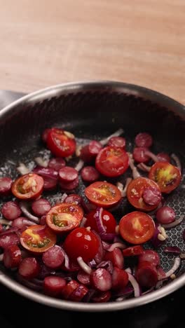 cooking sausage and vegetables in a pan