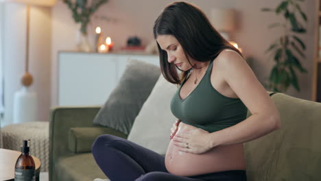 pregnant woman massaging her belly at home