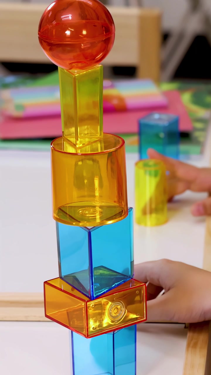 Anak dengan hati-hati menumpuk balok magnet transparan menjadi menara tinggi di meja kelas