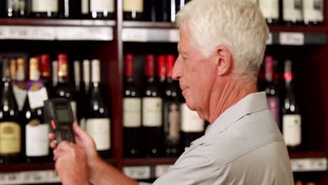 hombre mayor recogiendo un vino fuera de licencia