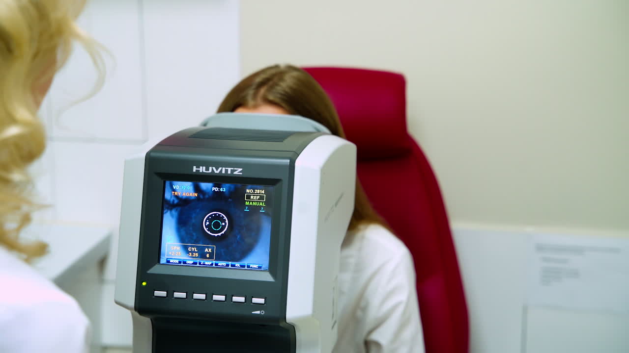 Eye ophthalmologist exam. Young woman at ophthalmologist doing examination of eyes, looking through autorefraktometer