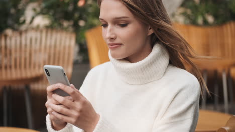 mujer caucásica enviando mensajes de texto en el teléfono inteligente al aire libre.