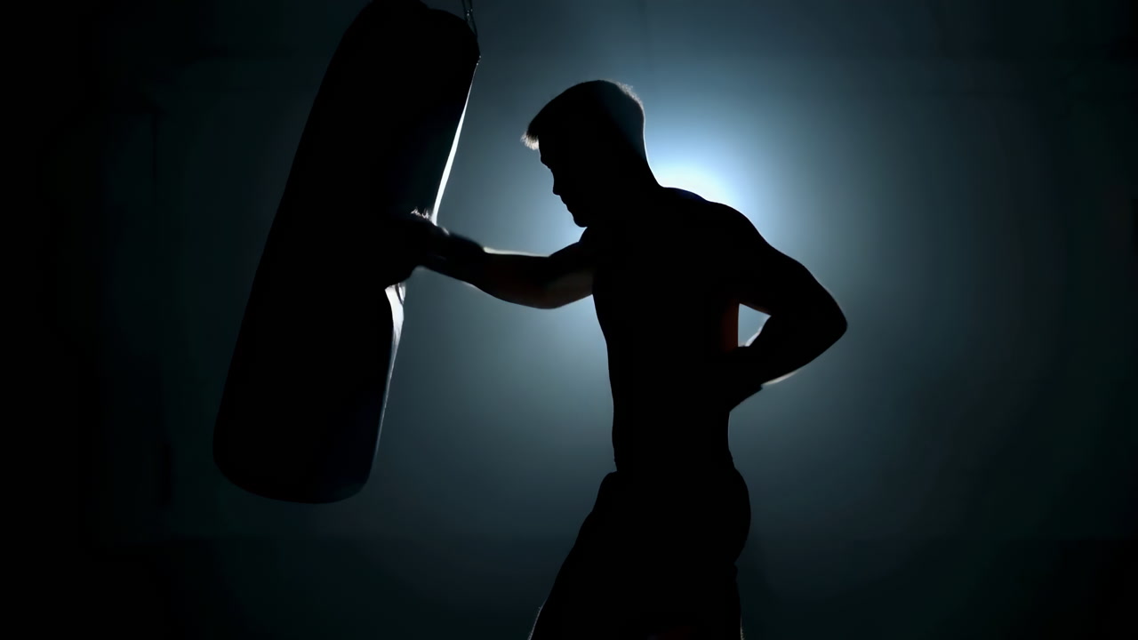 Silhouetted Boxer Training In Dark Gym With Heavy Bag, Backlit Rim Light Creates Dramatic Shadow, Powerful