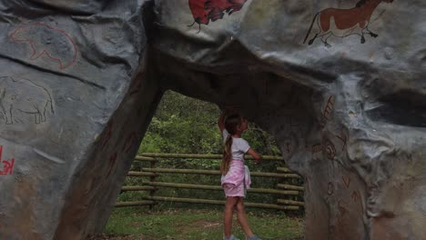 Little-girl-examines-large-stones-with-strange-markings,-panning-shot