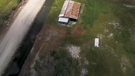 aerial shot of old structure with rusted metal roof on farm land