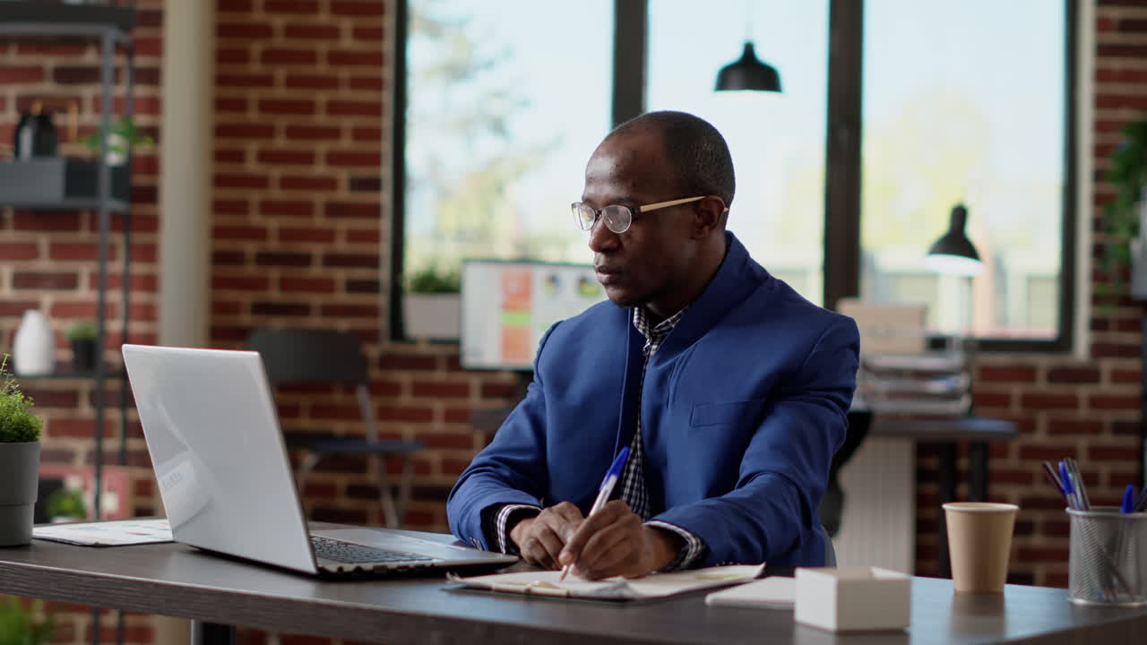 African american businessman taking notes on laptop