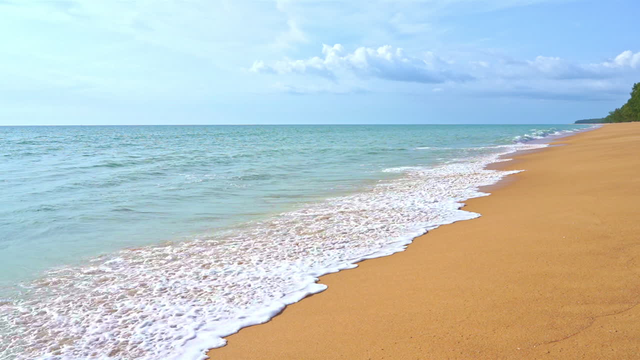 Zwolnione tempo fal rozbijających się o złotą plażę