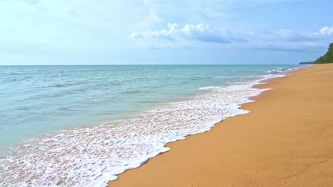 slow-motion of waves crashing on golden beach lockdown shot