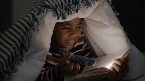 child reading under a blanket at night