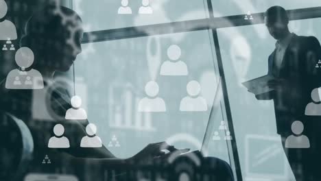 animation of digital icons over businesspeople using laptop and tablet