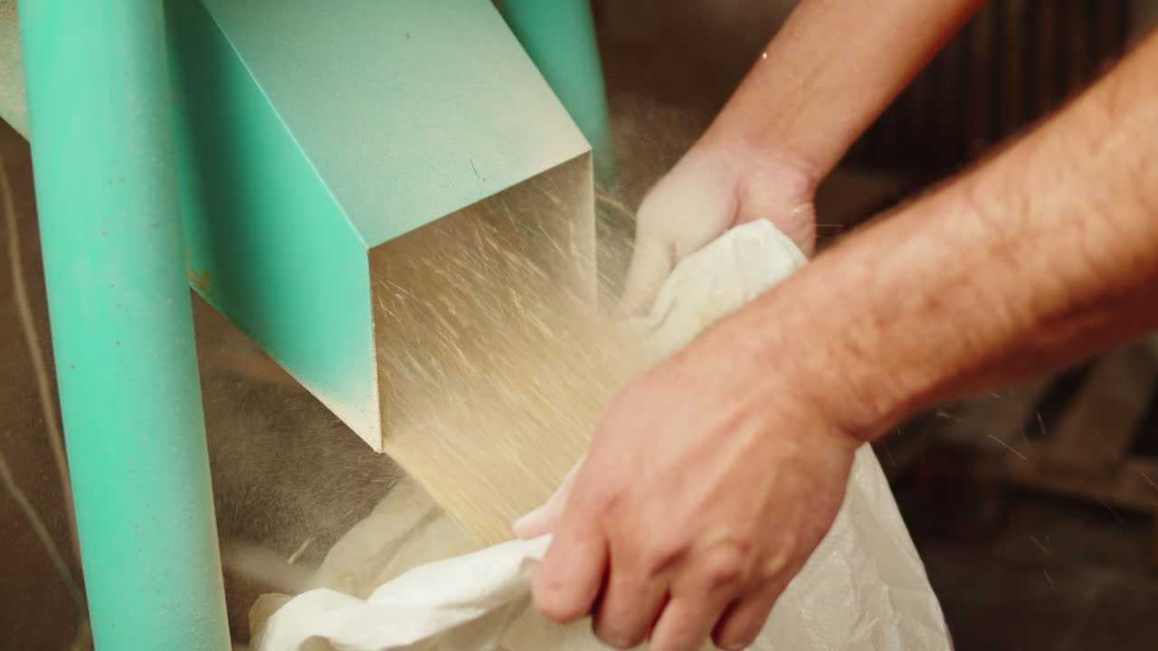 Craft beer production factory, brewery manufacture. Putting barley malt grains in sack close-up. Brewing, cooking alcohol in metal vats bottles