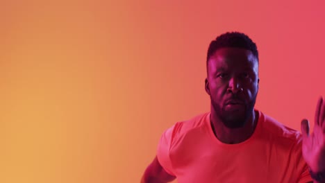 Video-Eines-Fokussierten-Afroamerikanischen-Männlichen-Athleten,-Der-Auf-Neonorangefarbenen-Blitzen-Läuft