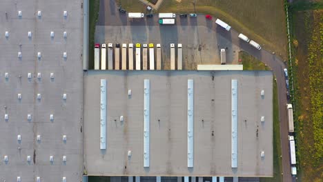 semi truck with cargo trailer is travelling along a parking lot of a warehouse in the logistics park