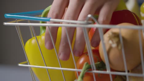 primer plano de la persona que toma alimentos frescos básicos de la cesta de la compra del supermercado