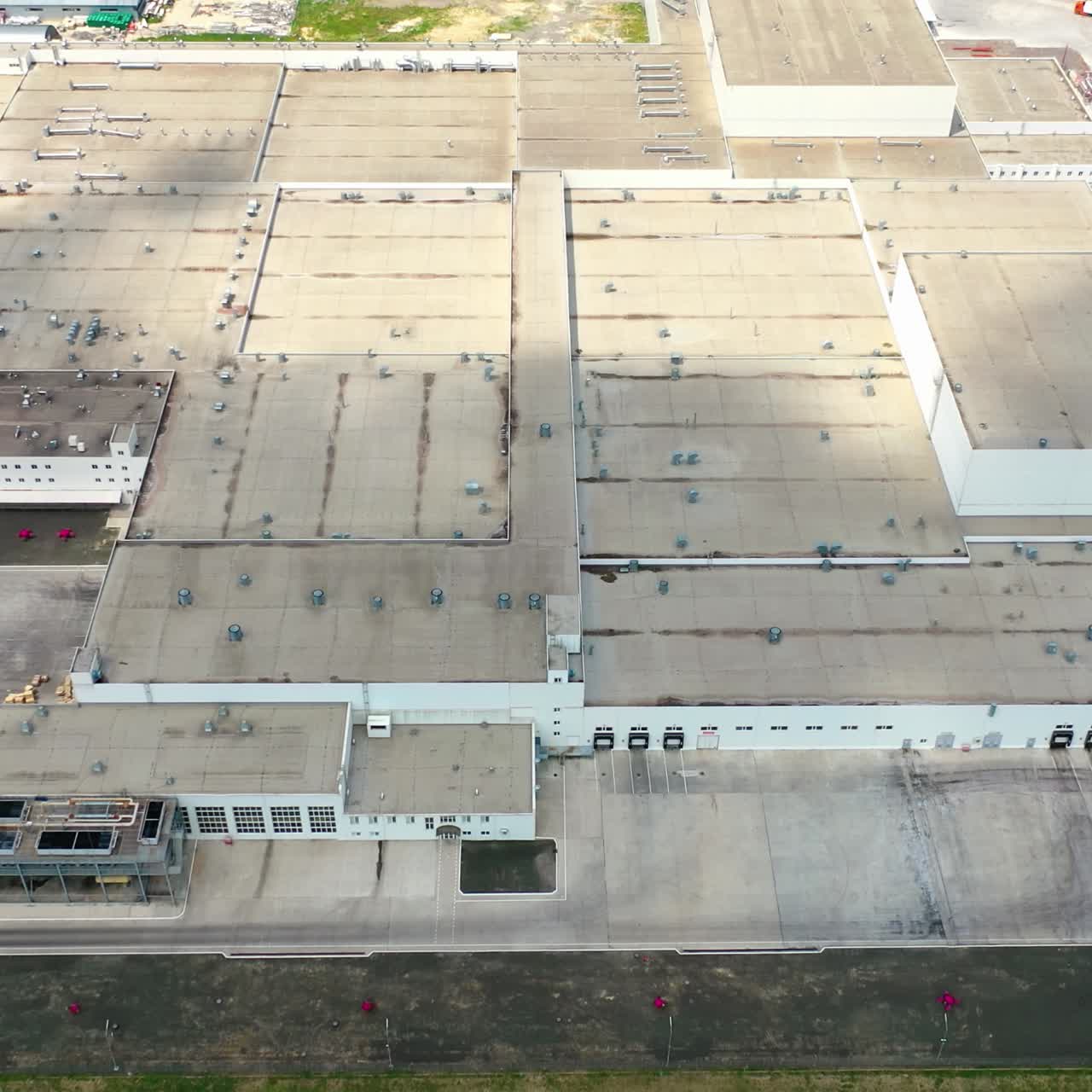 Roofs of the industrial plant. Many buildings constructed together and car parking places of a large modern factory. Top view