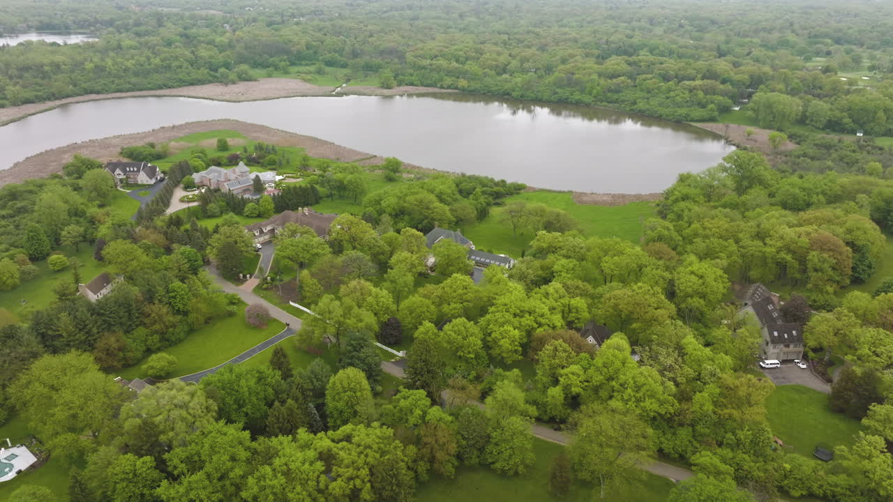 Little pond surrounded by green trees and grassy lawns. Private houses at the beautiful waterfront on summer day. Top view.