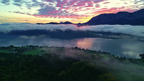 aerial view of attersee in austria with low-lying colorful clouds at sunrise, lush green below