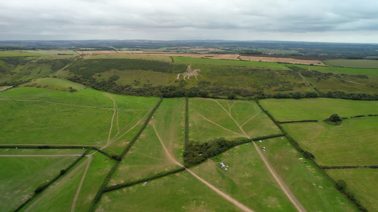 Osmington White Horse limestone figure art on hillside slope aerial view reversing across agricultural field