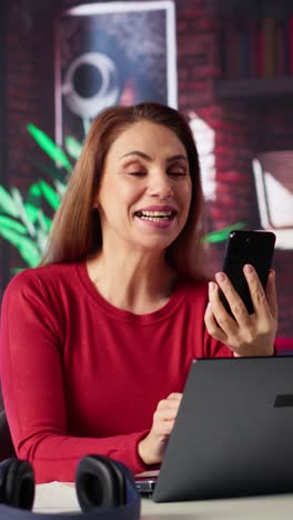 vertical video mature adult smiling and waving during a video call at home desk