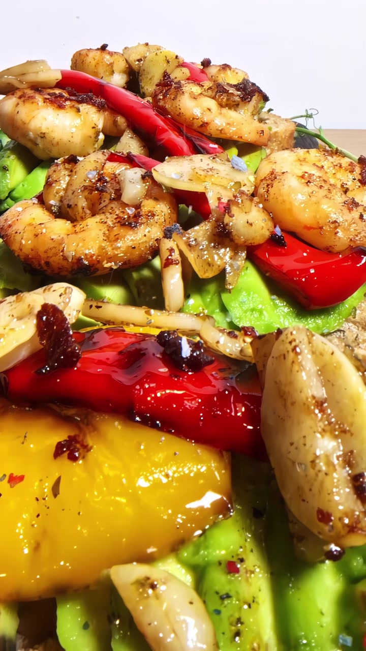 Gamberi succosi e avocado cremoso stratificati con peperoni vivaci su una fetta di pane tostato rustico, creando un piatto colorato e appetitoso.