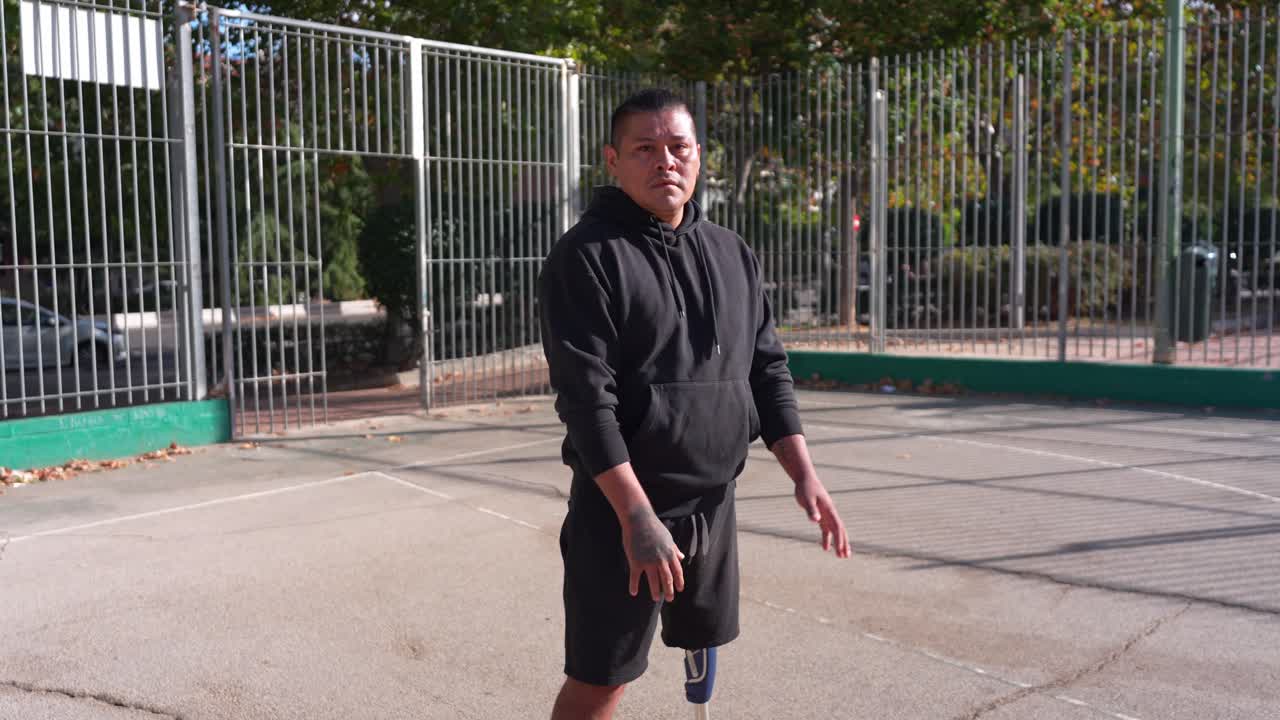 Uomo con gamba protesica che palleggia a basket su un campo all'aperto