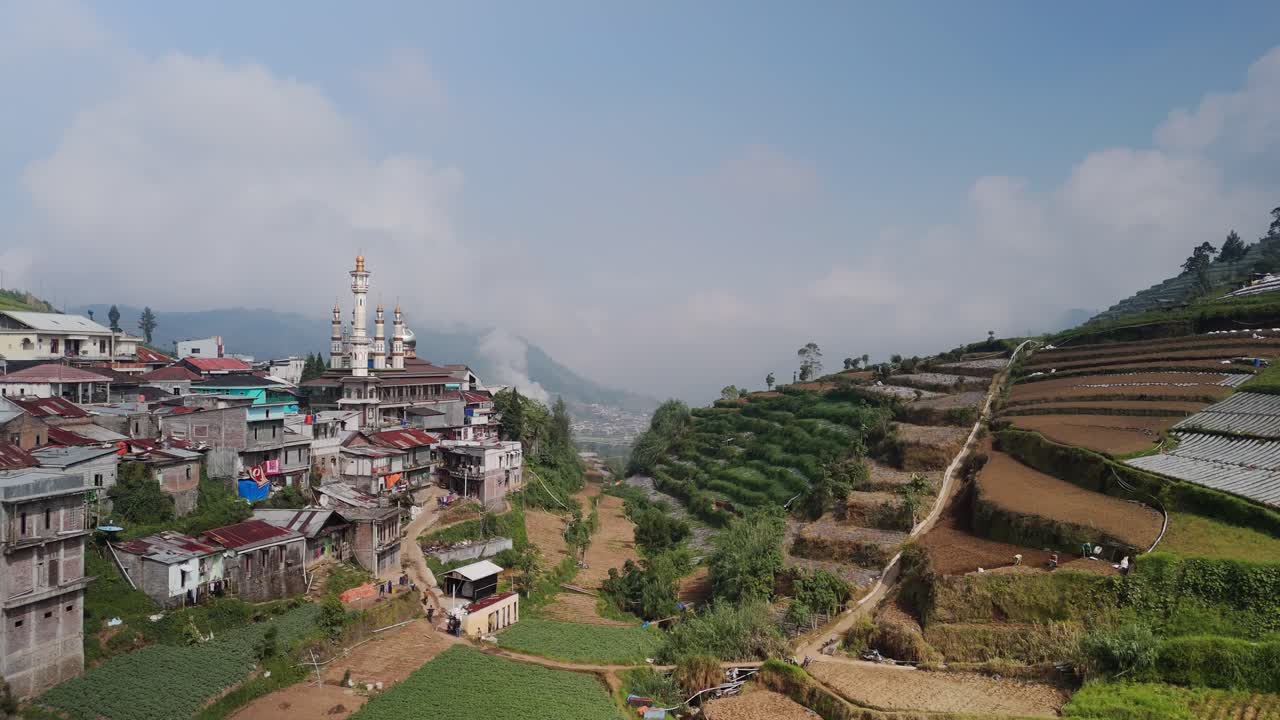 asentamiento de la ciudad de la ladera de la colina con mezquita decorativa en el valle agrícola montañoso