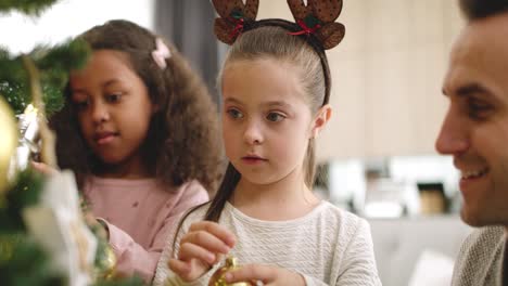 Handheld-view-of-girls-and-their-daddy-decorating-Christmas-tree