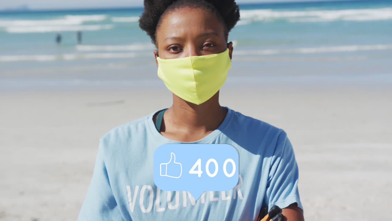 Animation of social media like notifications over african american woman in face mask on beach