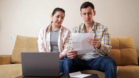 emotional couple reads apartment purchase agreement on couch