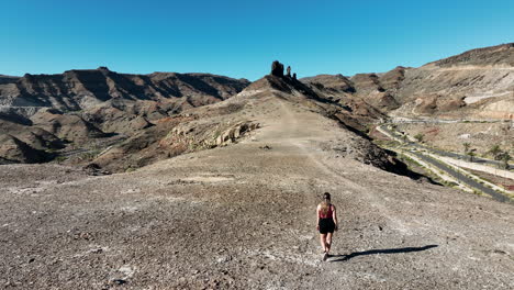 Mujer-Joven-Camina-En-Dirección-A-Una-Formación-Rocosa-Que-Está-Muy-Cerca-De-La-Playa-Medio-Almud-En-La-Isla-De-Gran-Canaria-Y-En-Un-Día-Soleado