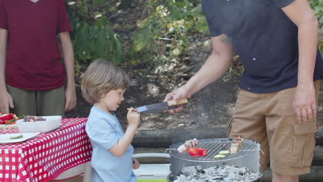 padre cariñoso dando a su pequeño hijo sabor a barbacoa