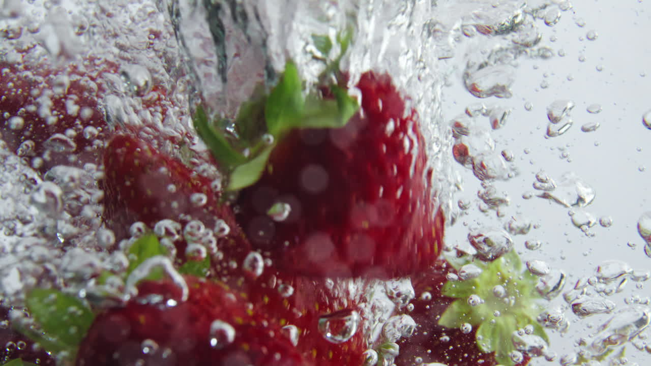 Nahaufnahme einer reifen Erdbeere, die in Superzeitlupe ins Wasser fällt. Beeren unter Wasser.