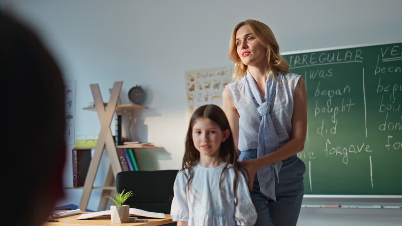 Little girl counting blackboard at elementary school lesson. Woman teacher