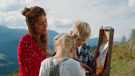 pintura positiva de la familia en las montañas. madre hijos creando obras de arte al aire libre