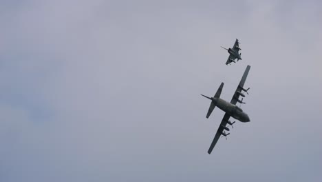 airbus a400m aircraft and the eurofighter fly close to each other at the airpower airshow, tracking across open blue sky