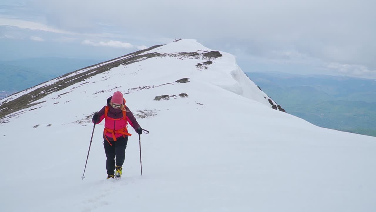 스키 폴을 들고 산 정상에서 눈 속을 트레킹하는 여자
