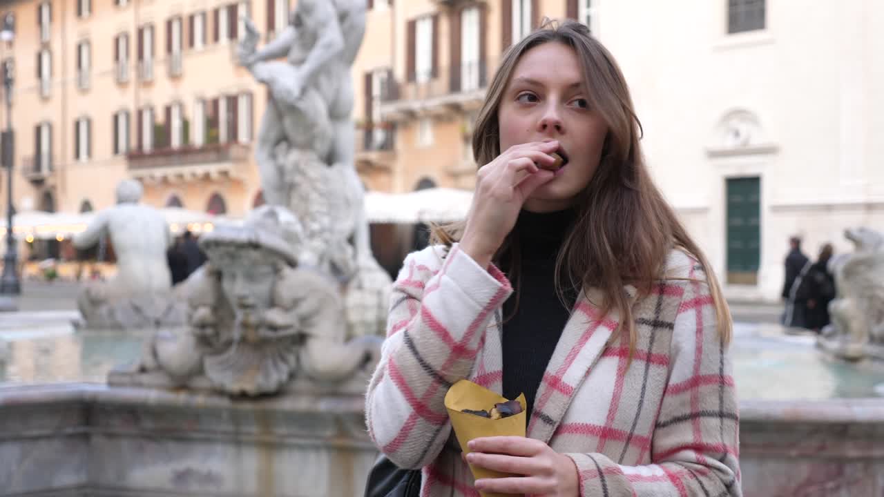 tourist eats chestnuts while enjoying the panorama of the monuments of Rome