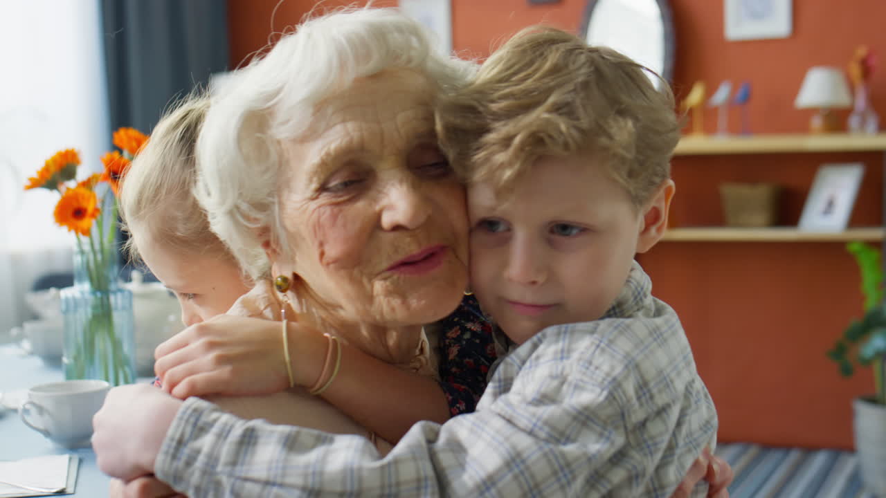 Bambini piccoli che abbracciano la nonna amorevole a casa