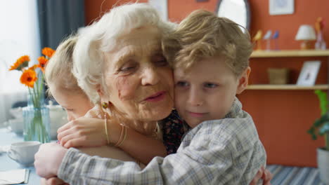 little children hugging loving grandmother at home