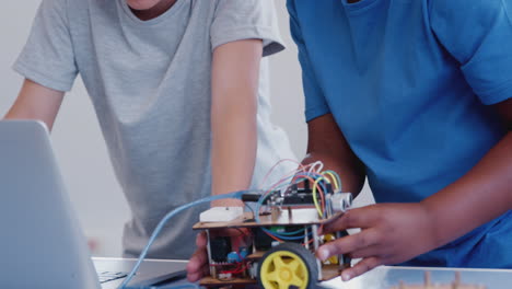 Two Male Students Building And Programing Robot Vehicle In After School Computer Coding Class