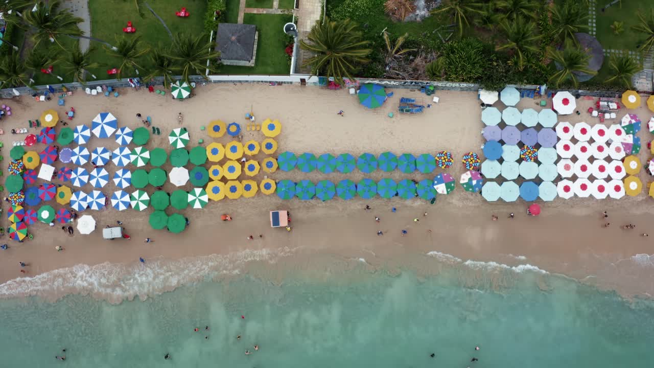 vista de pájaro de arriba hacia abajo toma aérea de sombrillas coloridas, vendedores de comida y turistas nadando en las piscinas naturales en el famoso puerto de galinhas o playa de puerto de pollo en pernambuco, brasil