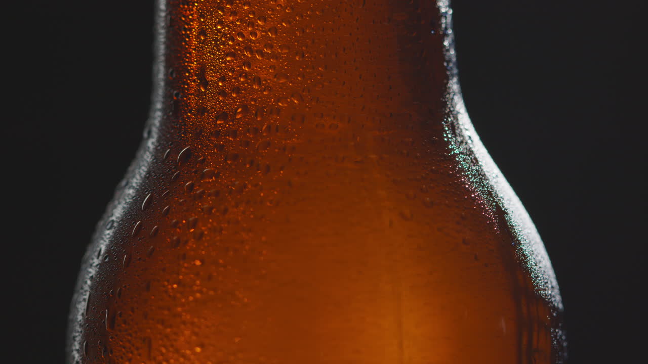 Close Up Of Condensation Droplets Running Down Revolving Bottle Of Cold Beer Or Soft Drink