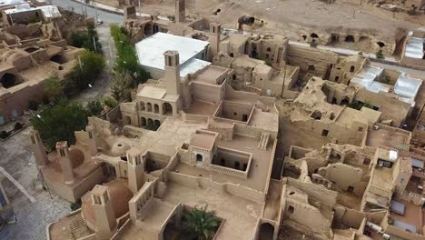 aerial-drone-shot-view-of-a-desert-city-in-aqda-ardakan-like-morocco-architecture-sand-clay-adobe-mud-brick-house-village-in-rural-area-brown-color-square-yard-passive-design-in-Persia-middle-east