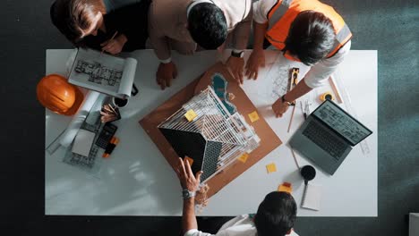 Top-view-of-team-inspect-house-model-while-manager-hold-blueprint.-Alimentation.