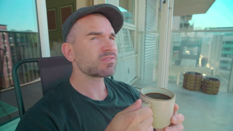 a man wearing traditional flat cap drinking coffee at the veranda